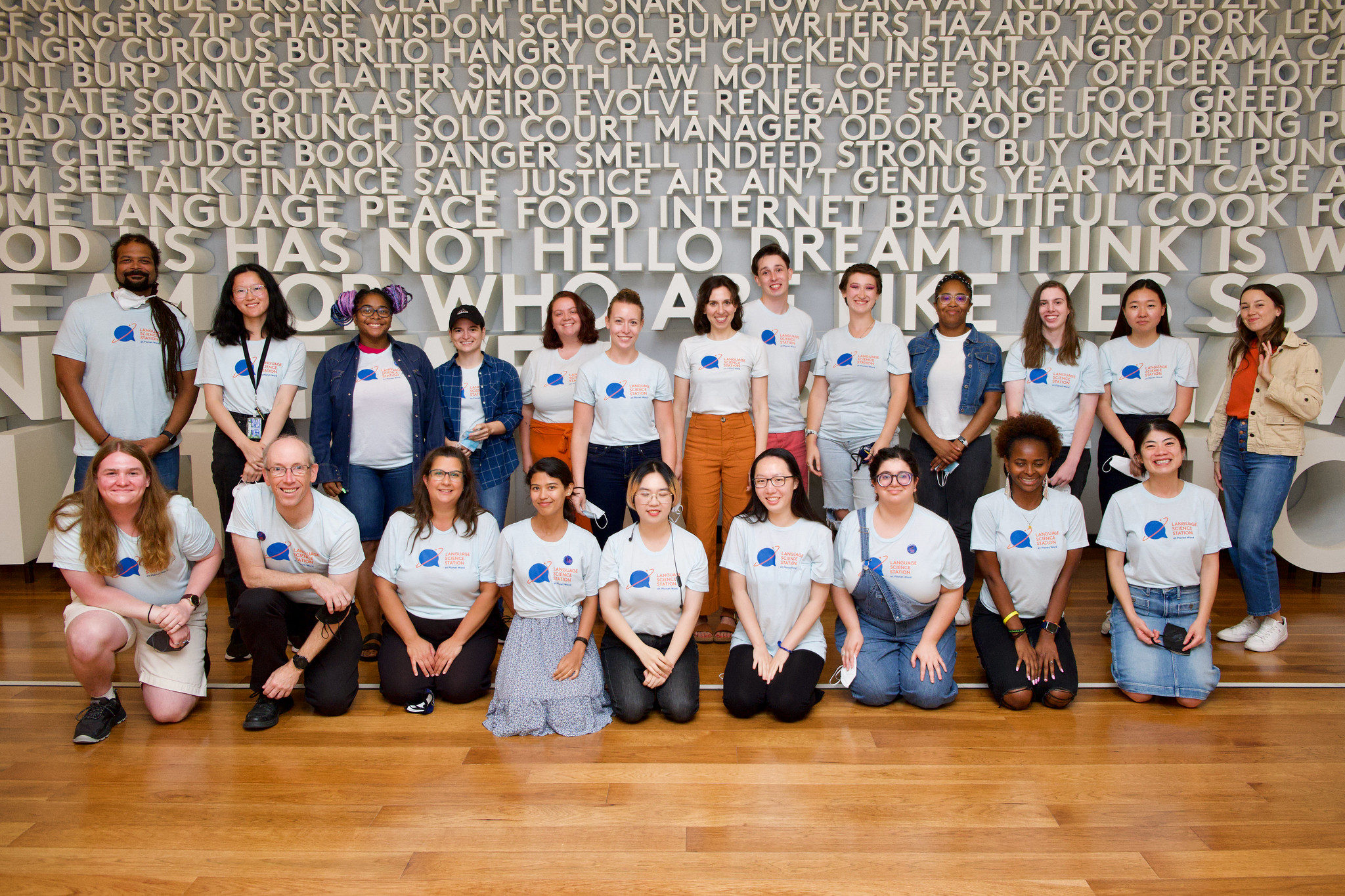 A couple dozen students and teachers, in identical t-shirts, standing in front of wall of sculpted words at the Planet Word museum in DC.