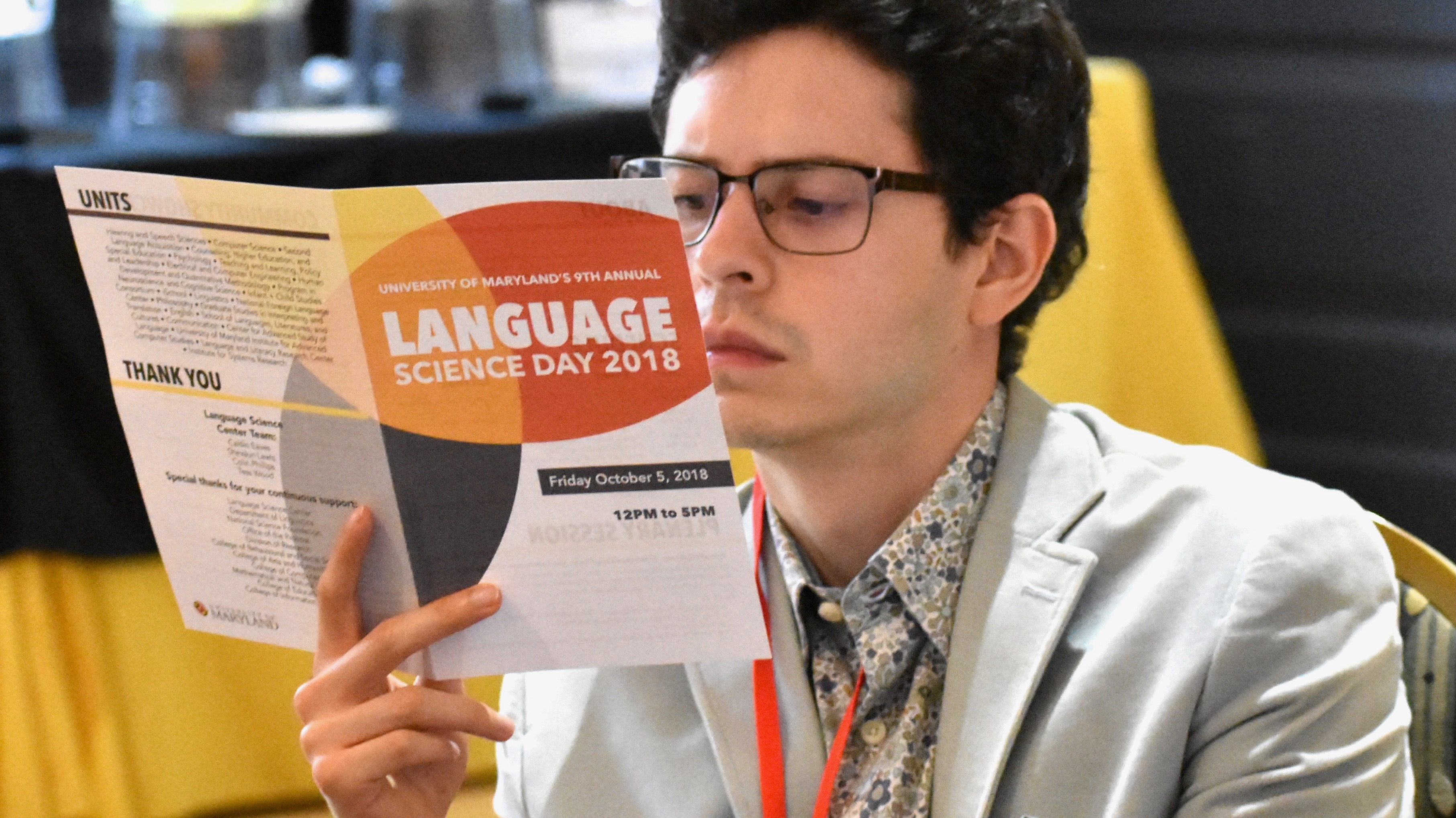 A young man reading a brochure, with a skeptical look.