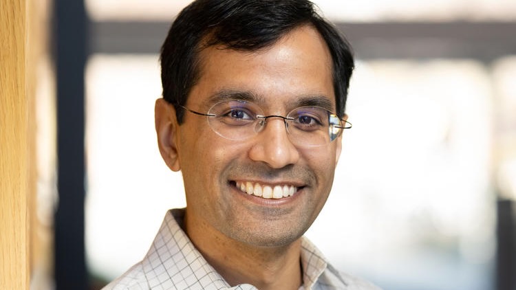 Professional headshot of a man, smiling.