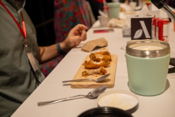 Hot wings and ice cream tubs sit at a table 