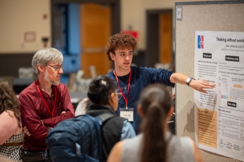 Person gestures to academic poster at conference